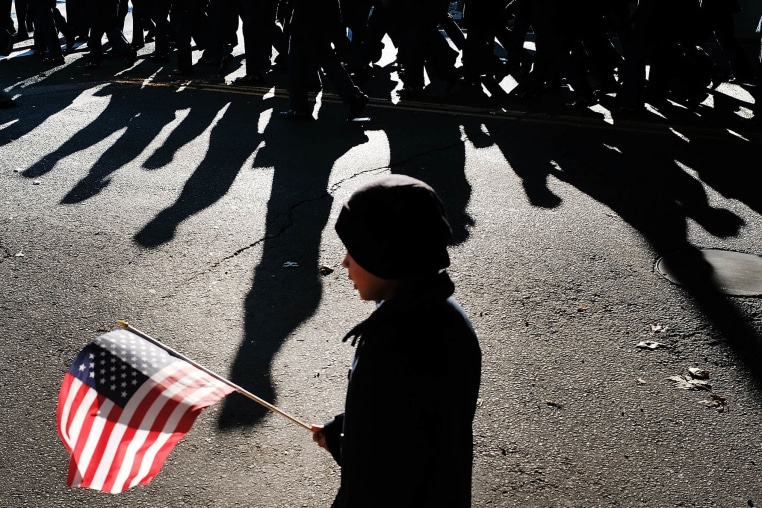A child holds an American Flag as the Veterans Day Parade passes.